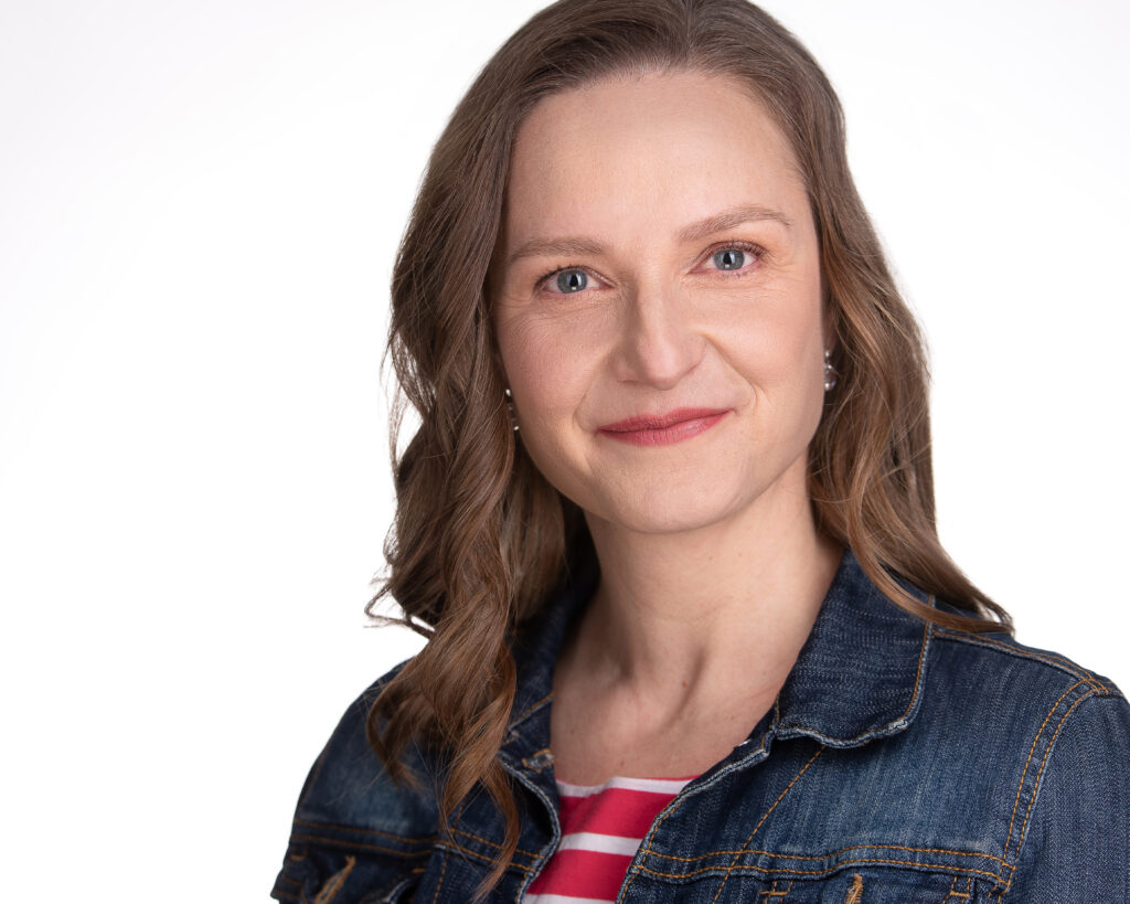 Neisz Lauráról fehér háttér előtt, farmer blúzban.